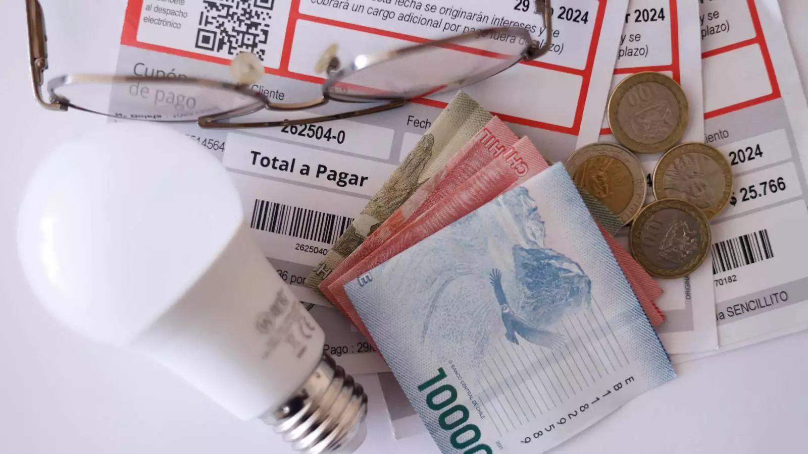 Cuenta de la luz, una ampolleta y billetes de distinta denominación
