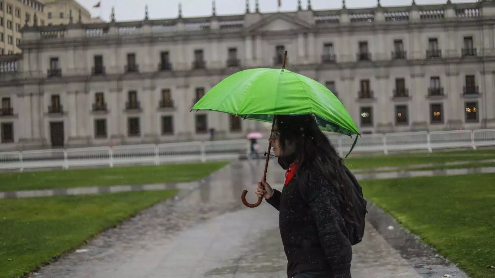 Persona con un paraguas bajo la lluvia frente a La Moneda