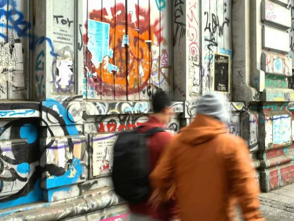 Muro rayado mientras transeúntes transitan por las calles de Valparaíso.